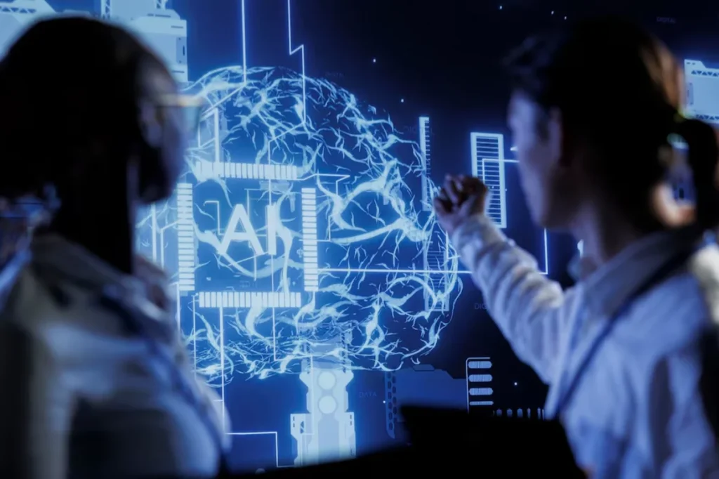 Two people analyzing a holographic display of a brain integrated with circuit patterns and data charts in a dark, futuristic setting.